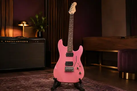 Guitare électrique Eart TL-380 rose à humbuckers, posée sur un support dans un studio chaleureux