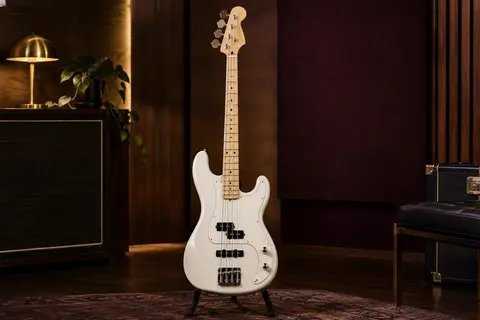 Basse électrique blanche à quatre cordes avec micros Precision et Jazz, présentée sur un support en studio