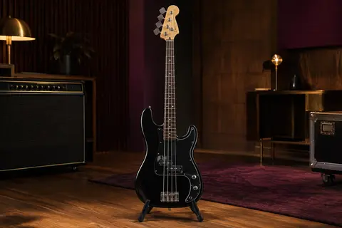 Basse électrique noire Squier Mini Precision Bass à quatre cordes sur un support dans un studio chaleureux
