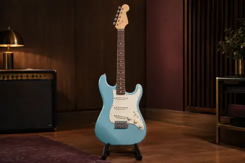 Guitare électrique Mini Stratocaster bleue à six cordes, présentée seule sur un support dans un studio chaleureux.