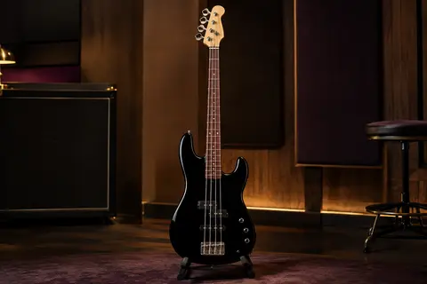 Basse électrique noire à quatre cordes, manche en érable et chevalet chromé, présentée sur un support en studio.