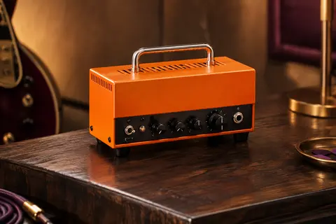 Tête d’ampli guitare Orange Micro Terror compacte, finition orange, présentée seule sur un support en bois sombre.