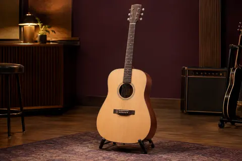 Guitare folk Yamaha F310 à table en épicéa, posée sur un support dans un studio chaleureux.